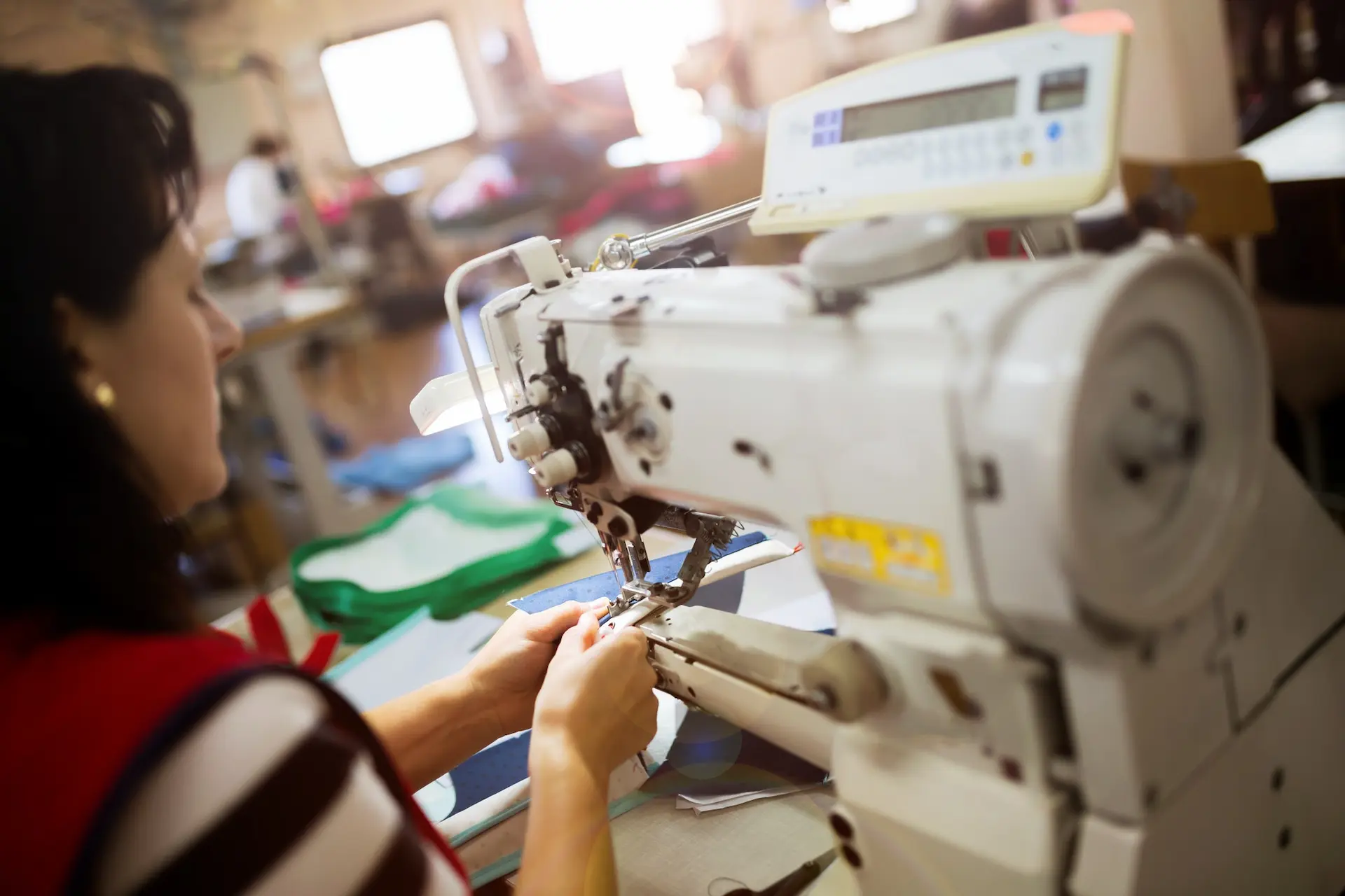 Operario operando máquina de coser industrial para confección de uniformes